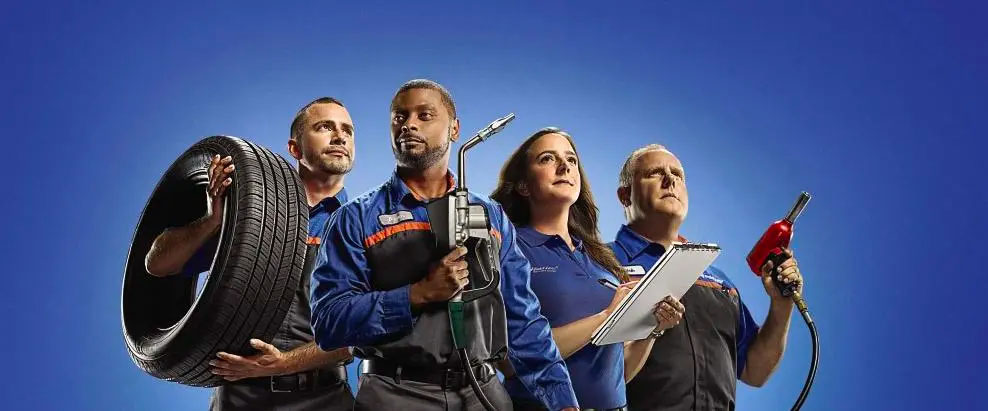 Automotive team with tools and tire against blue background, showcasing car maintenance expertise.