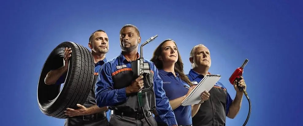 Professional auto repair team with tools, tire, clipboard, and fuel nozzle, showcasing teamwork and expertise.